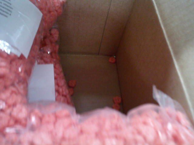 Spilled Franken berry cereal surrounded by bags of it in a cardboard box.